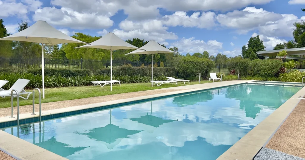 Modern rectangular residential swimming pool with poolside lounge seating and shade umbrellas
