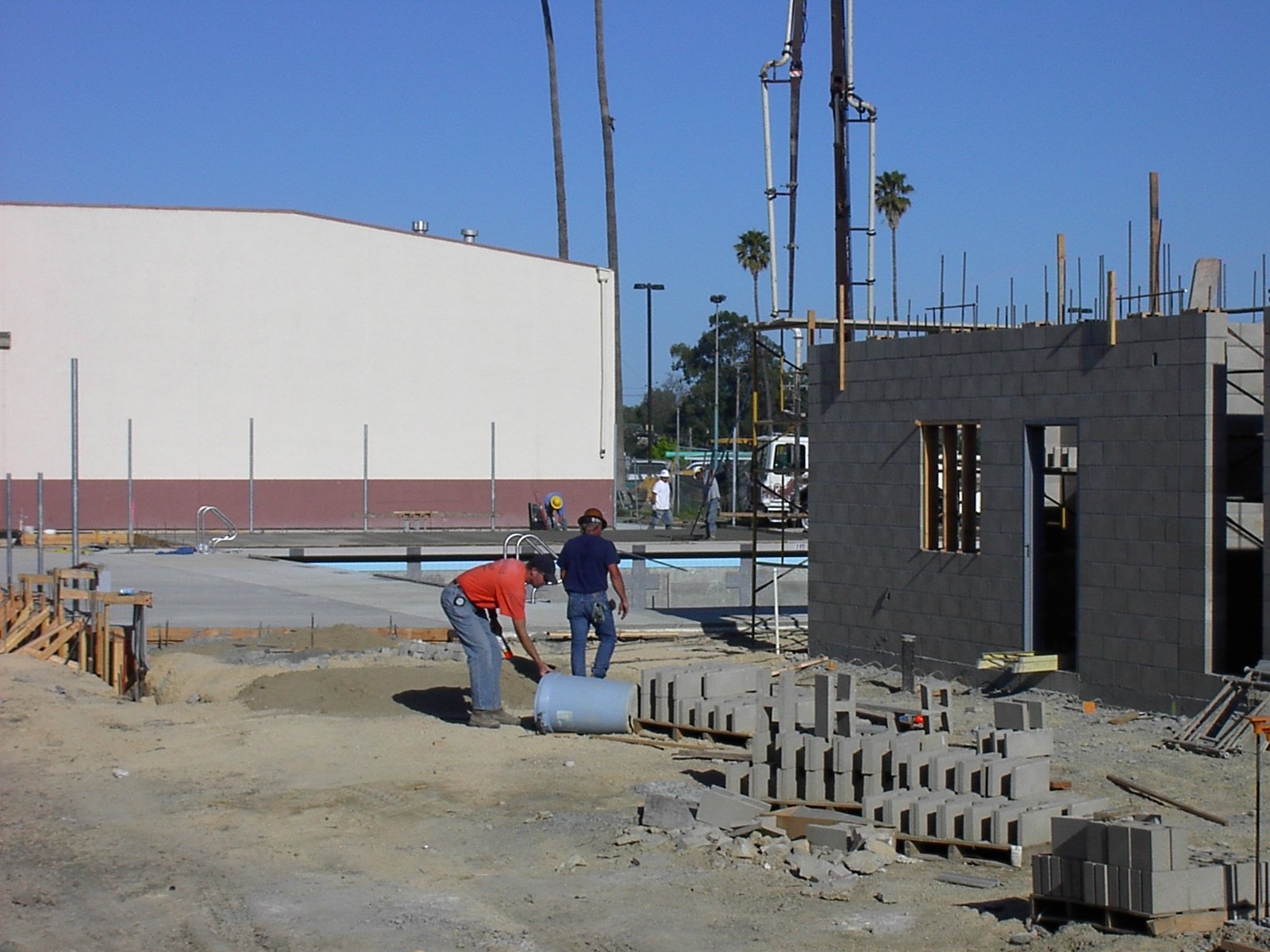 Construction crew building a swimming pool and adjacent structure at a job site, illustrating the contractor work behind a pool project