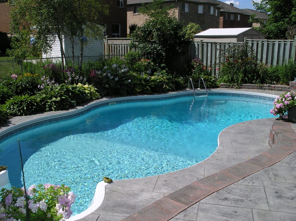 A finished in-ground backyard swimming pool surrounded by landscaping, the kind of project worth planning ahead for